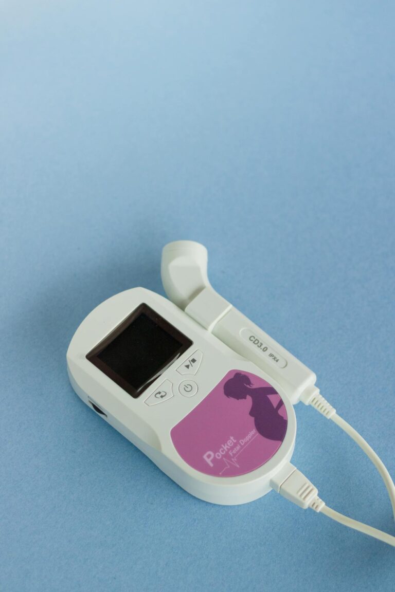 High-quality image of a portable fetal doppler monitor on a blue surface, ideal for medical product use.